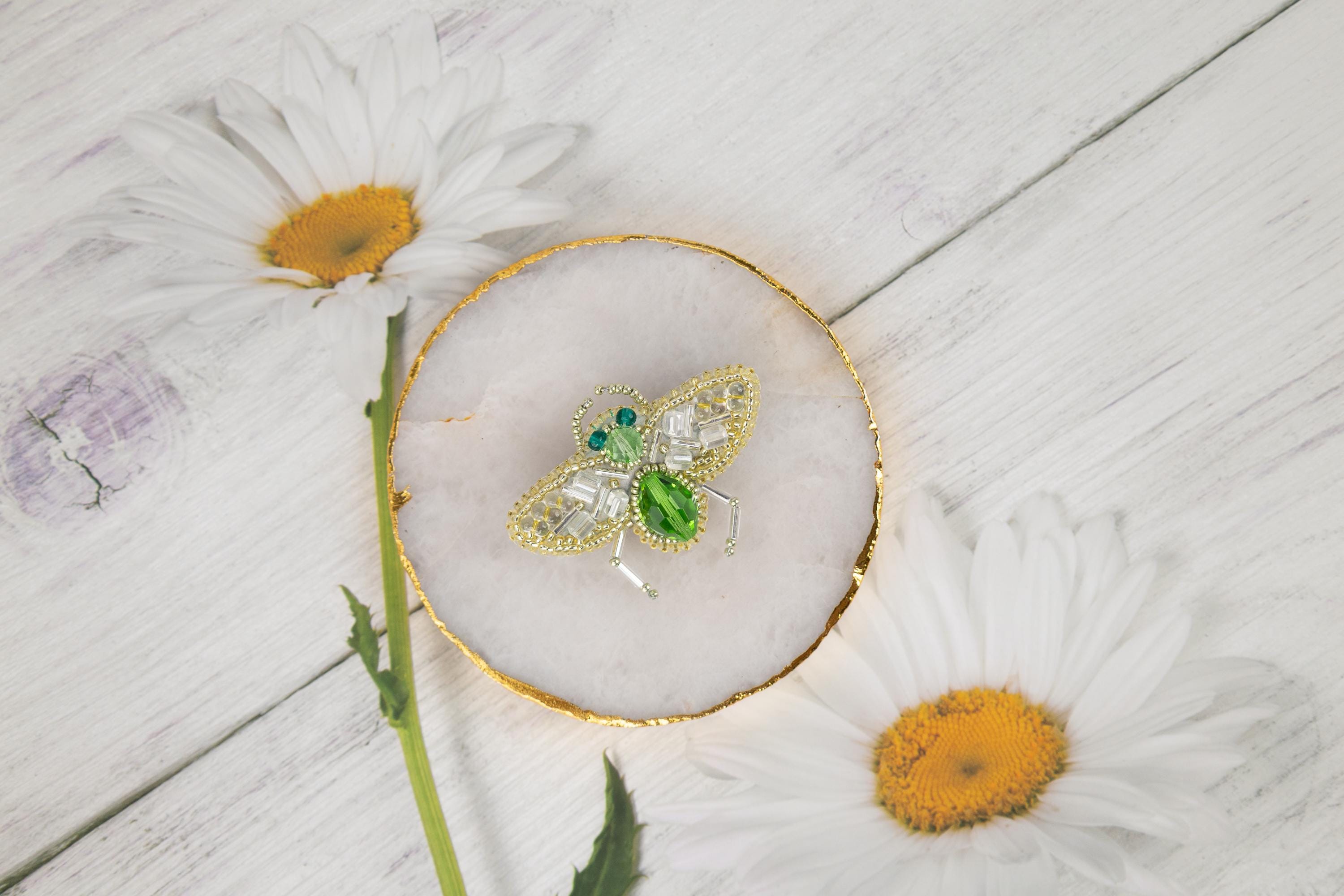 daisies and a brooch sitting on a white wooden surface